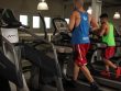 Two men running on treadmills in a modern gym, promoting fitness and health.